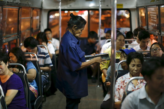 Pranom Chartyothin, a 72-year-old bus conductor, sells and collects bus tickets in downtown Bangkok, Thailand, February 3, 2016. Such scenes will only become more common in Thailand as its population rapidly ages, unlike its neighbours with more youthful populations. The World Bank estimates the working-age population will shrink by 11 percent by 2040, the fastest contraction among Southeast Asia's developing countries. Thailand's stage of economic development, the rising cost of living and education, and a population waiting longer to get married are among the reasons it is ageing more quickly than its neighbours. An effective contraception programme in the 1970s also played a part, said Sutayut Osornprasop, a human development specialist at the World Bank in Thailand. Picture taken February 3, 2016. REUTERS/Jorge Silva TPX IMAGES OF THE DAY - RTX269SM